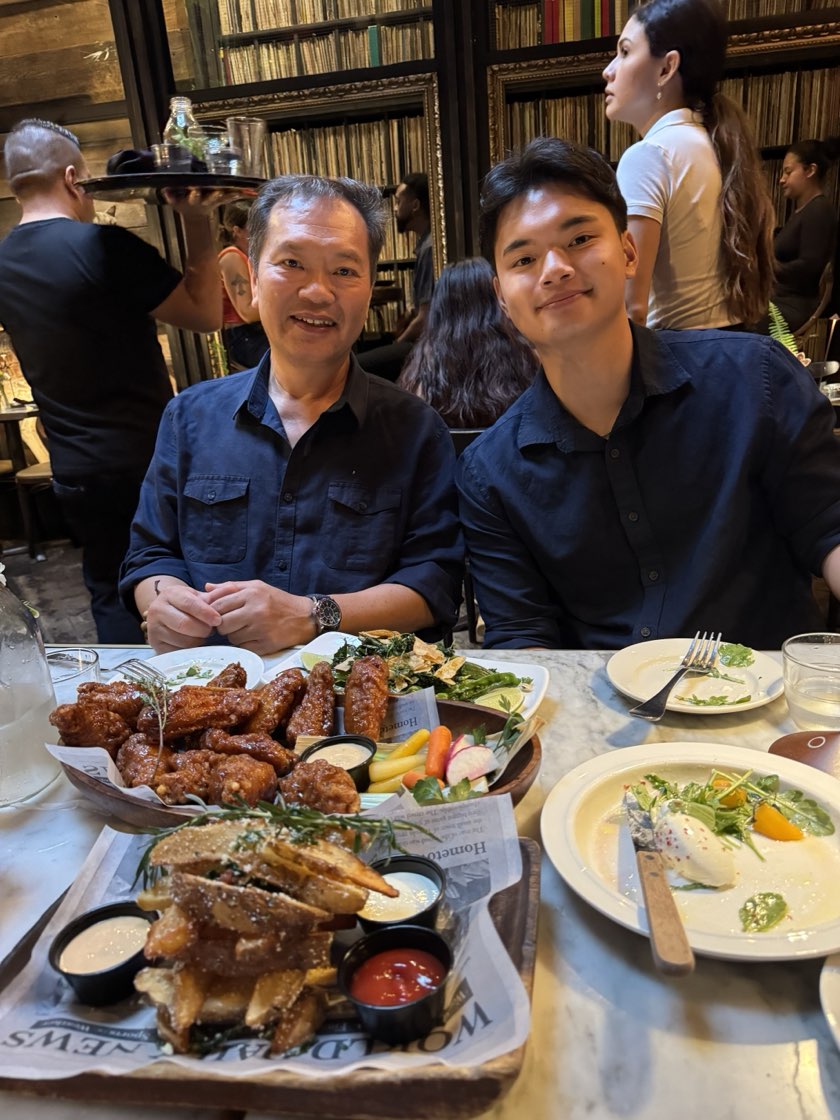 Jonathan and his dad at a restaurant table, a plate of wings in front of them