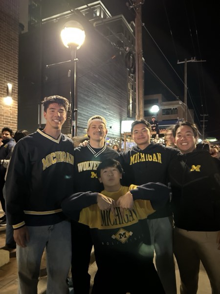 Jonathan and four friends in Michigan gear on a street at night after a game
