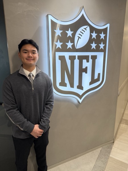 Jonathan beside the illuminated NFL shield at the league's New York office
